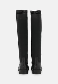 Botas negras hasta la rodilla que presentan una parte inferior de cuero liso y una parte superior de tela texturizada, con una suela resistente y un discreto detalle de logo.