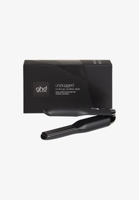 Lisseur de cheveux sans fil noir au design épuré, placé devant sa boîte d'emballage noire étiquetée "unplugged on the go cordless styler."