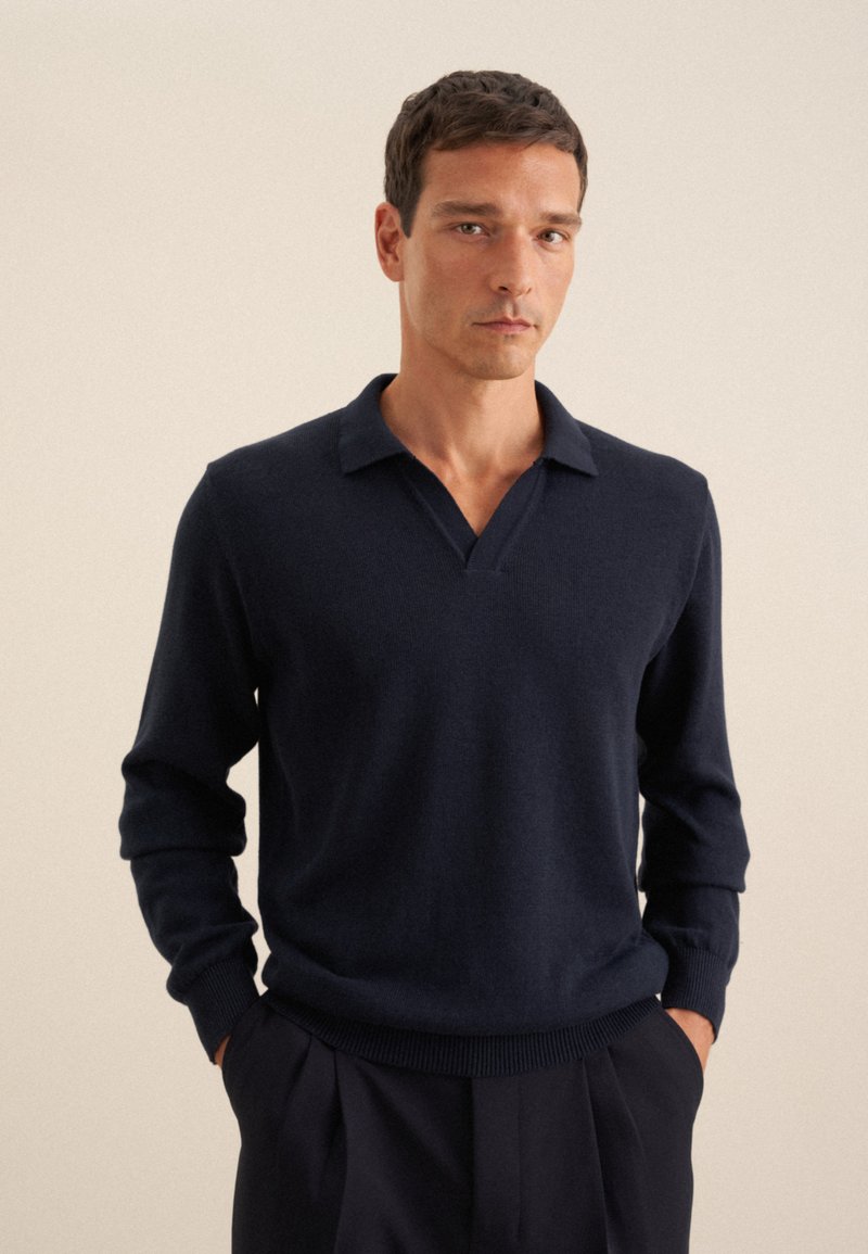 Marineblaues V-Ausschnitt-Pullover aus feinem Strickstoff mit langen Ärmeln und geripptem Saum. Der Kragen hat ein flaches, offenes Design für eine lässige Passform.