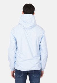 Giacca leggera azzurro chiaro con cappuccio, polsini elasticizzati e texture liscia. Presenta un design minimalista e senza branding visibile.