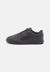 Schwarze Puma-Sneaker mit einem Obermaterial aus glattem Leder, perforierter Zehenpartie, flachen Schnürsenkeln, dicker Gummisohle und dem Markenzeichen auf der Seite.