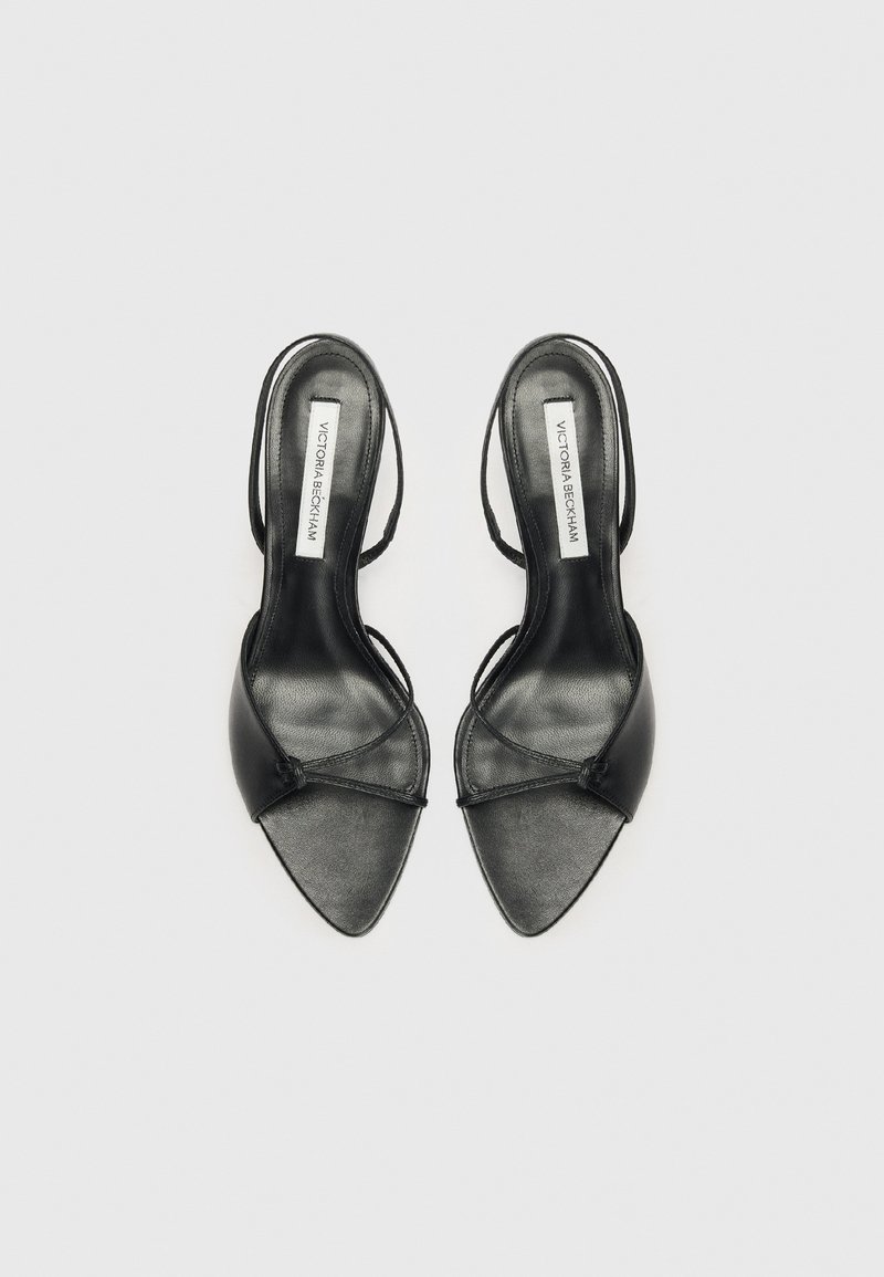 Escarpins slingback noirs en cuir avec bout pointu, dotés de fines lanières et d'une étiquette "Victoria Beckham" sur la semelle intérieure, présentés de dessus sur un fond blanc.