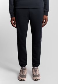 Marine joggers van zachte stof met geribbelde manchetten, voorzien van zijkanten en een voorzak. Gecombineerd met beige sneakers.