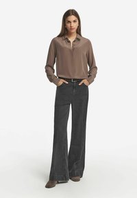 Brun satin blus med lång ärm i kombination med grå vida jeans. Outfiten har en krage och ett bälte i midjan.