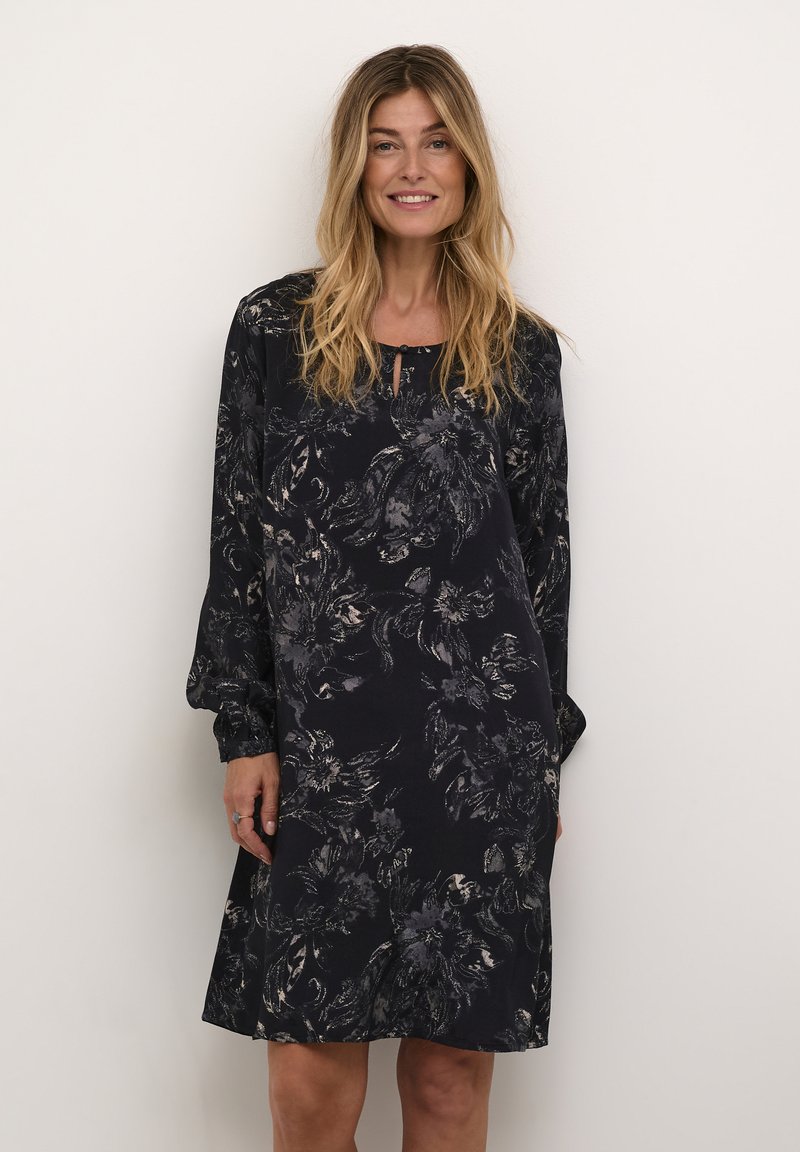Schwarzes Langarmkleid mit floralem Druck in Grautönen, mit rundem Ausschnitt und einem Schlüsselgrubendetail an der Vorderseite. Weicher Stoff.