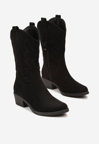 Bottes de cowboy en daim noir avec une forme structurée, dotées de strass décoratifs, de sangles de traction et d'un petit talon bloc. Fermeture éclair sur le côté incluse.
