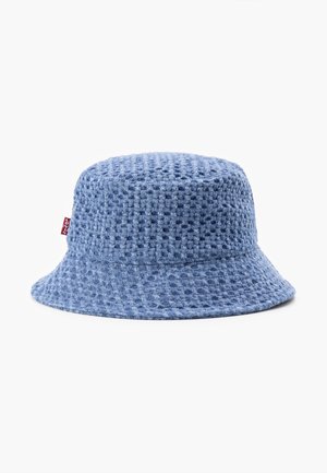 Chapeau bob bleu en tissu tricot gaufré texturé avec une petite étiquette en tissu rouge sur le côté, posé sur un fond blanc uni.