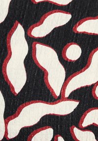 Tessuto nero con una superficie texture, caratterizzato da un motivo astratto bianco e rosso di forme curve e cerchi.