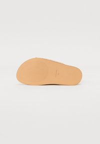 Brun sandaled såle med teksturert grep mønster. Materialet ser glatt ut, subtilt designet med en avrundet form. Størrelse 37 merket på bunnen.