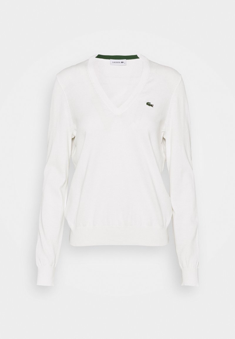 Pull blanc à manches longues avec col en V, poignets et ourlet côtelés, arborant un petit logo crocodile vert Lacoste sur la poitrine gauche.