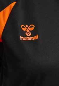 Sort og orange sportstrøje med en orange stiliseret bi-logo og teksten "hummel" på brystområdet.