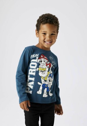 Blaues Langarm-T-Shirt mit "PAW Patrol"-Charakteren in weißer und gelber Druck. Schwarze Hose, weiches Baumwollmaterial, einfacher runder Ausschnitt.