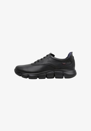 Zapatilla deportiva de cuero negro con un empeine suave, puntera redondeada y suela segmentada distintiva. Cuenta con cordones y un sutil logotipo en el lateral.