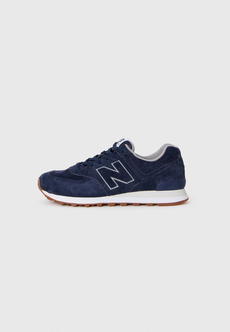 Baskets New Balance en daim bleu marine avec semelle intermédiaire blanche, semelle extérieure en gomme et grand logo "N" sur le côté.