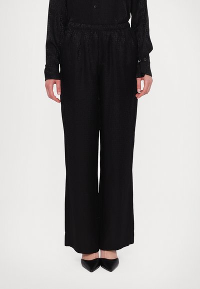 Pantalon noir ample avec une texture subtile et une taille élastique, associé à une chemise à manches longues à boutons assortie.
