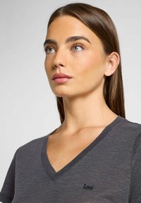 Grå v-hals t-shirt lavet af let materiale, med subtil tekstur og broderet logo på venstre bryst.