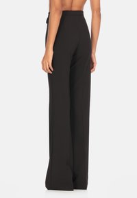 Pantaloni neri a vita alta, con gamba larga, realizzati in tessuto morbido e con un design pulito, caratterizzati da una cucitura posteriore e senza hardware visibile.