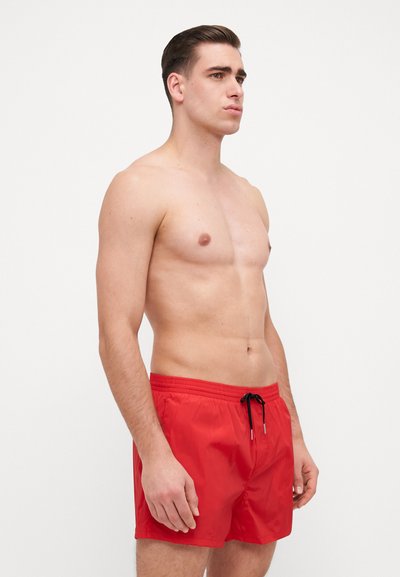 Costume de baie roșu, realizat dintr-un material ușor, având un brâu elastic cu șnur. Textură netedă, tăiere până la genunchi.