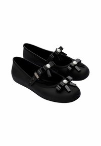 Zapatos planos negros hechos de un material suave, con dos lazos decorativos y acentos de perlas en la parte frontal. Presentan una forma de punta redondeada.