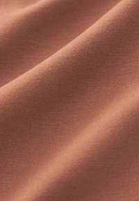 Tissu texturé d'un brun rougeâtre avec un motif tissé, présentant une surface lisse et un léger éclat, adapté pour des vêtements ou de l'ameublement.