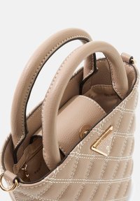 Beige gewatteerde handtas met dubbele handvatten, gouden hardware en een gestructureerd oppervlak. Inclusief een binnenvak en een merkaccent.