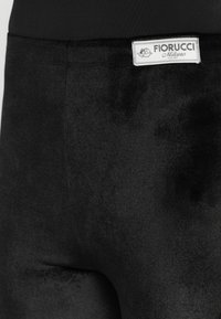 Black velvety leggings feature a smooth texture with a subtle sheen. The waistband displays a white label with "Fiorucci Milano" branding.