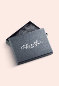 Graue Schmuckschatulle mit strukturiertem Finish und offenem Deckel, der schwarzes Seidenpapier im Inneren zeigt. Mit weißem eingeprägtem Logo: "Sofia Milani JEWELS."
