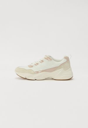 Bílé a jemně béžové tenisky s texturovaným svrškem, šněrováním a robustní podrážkou. Materiály: hladké a semišové akcenty.