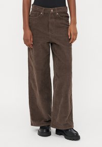 Bruine corduroy wijde broek met een gestructureerd oppervlak, voorzien van een knoop- en ritssluiting, frontzakken en een hoge taille.
