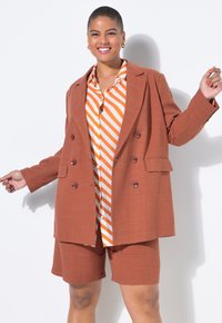 Hnědý lněný dvouřadý blejzr přes oranžovo-bíle pruhovanou košili a odpovídající šortky, zdobený knoflíky a s volným střihem.