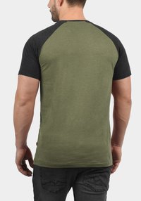 Short-sleeve t-shirt with a dark grey raglan design and olive green body. Made from soft fabric, features a round neckline and a relaxed fit.