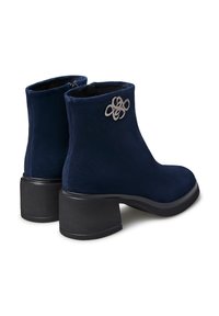 Stivaletti alla caviglia blu navy in suede con tacco a blocco, caratterizzati da un accento decorativo argentato sul lato e una texture liscia.