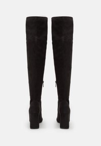 Bottes en daim noires au-dessus du genou avec un léger éclat, présentant un talon bloc haut, des fermetures éclair latérales et une texture lisse.