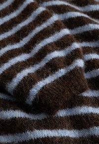 Miękka, brązowa dzianina z poziomymi jasnoniebieskimi paskami, pokazująca zbliżoną fakturę i fałdy.