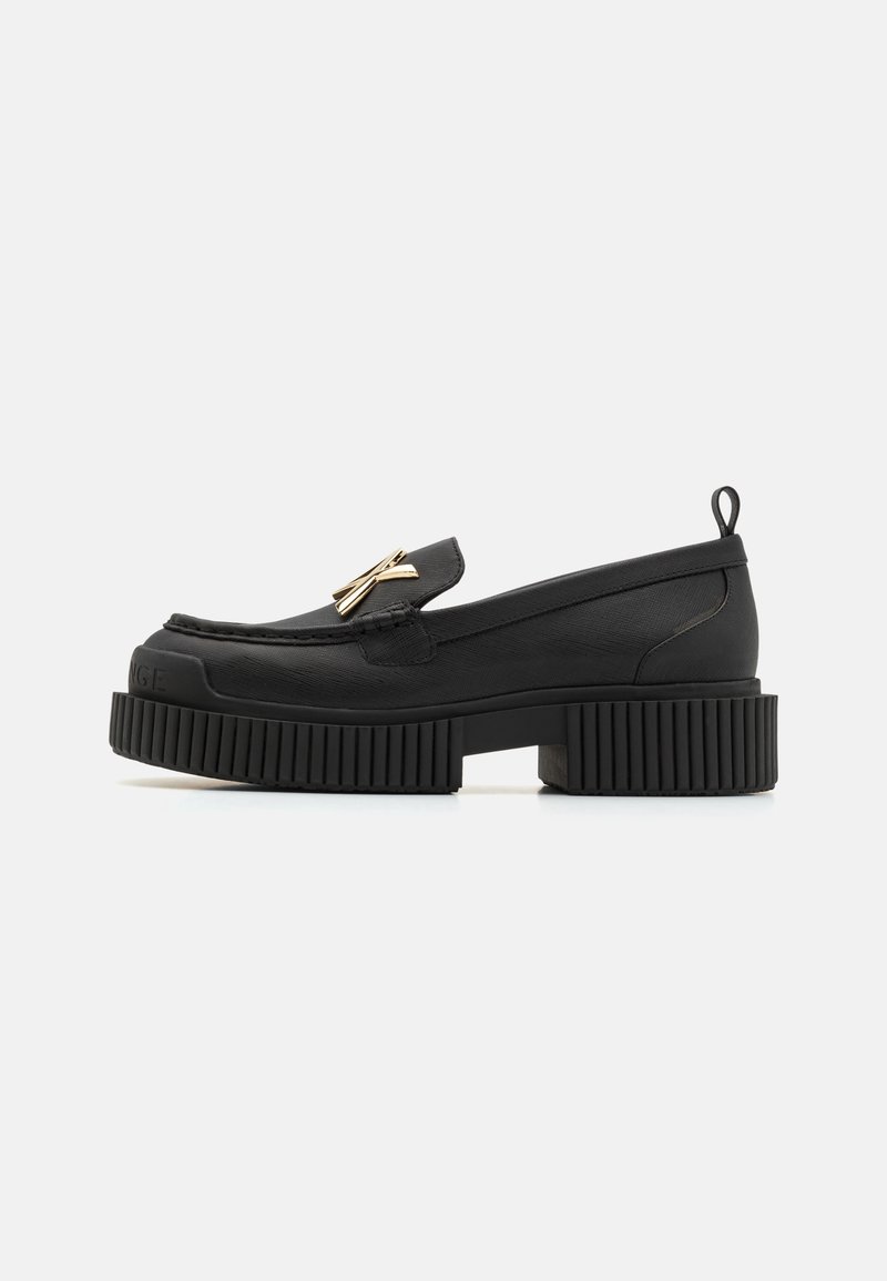 Mocassin en cuir noir avec semelle épaisse à rainures, détail nœud doré sur le cou-de-pied, petit talon carré et languette à l'arrière du col.