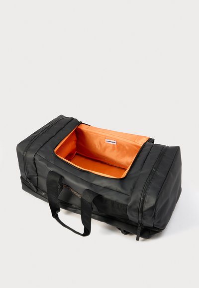 Μαύρη ορθογώνια τσάντα duffel με διπλές λαβές, εντελώς ανοιχτό φερμουάρ στην κορυφή που αποκαλύπτει φωτεινό πορτοκαλί εσωτερικό και πλαϊνές τσέπες με φερμουάρ.