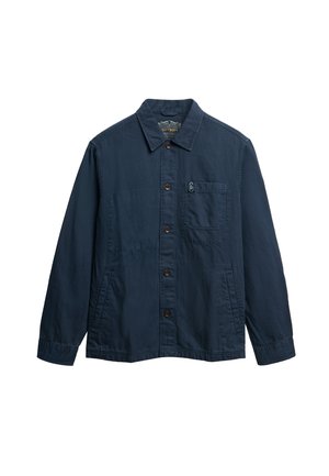Chaqueta de algodón color azul marino con cierre de botones en la parte delantera, cuello puntiagudo, un bolsillo en el pecho y dos bolsillos laterales. Presenta un logo sutil en el bolsillo.