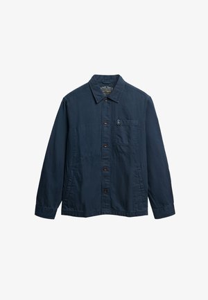 Chaqueta de algodón color azul marino con cierre de botones en la parte delantera, cuello puntiagudo, un bolsillo en el pecho y dos bolsillos laterales. Presenta un logo sutil en el bolsillo.