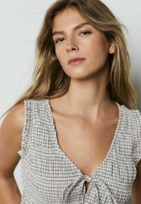 Helehall kaelusega kleit V-kaelusega, millel on kogutud tekstuur ja ees lipsu detail, tekstuurse kanga ja peente triipudega.