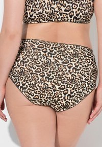 Culotte taille haute à imprimé léopard, dotée d'un tissu lisse, de garnitures noires et d'un design de dos courbé avec une finition sans couture.