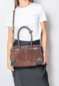 Borsa in suede marrone con dettagli in pelle, dotata di due manici superiori e di una tracolla removibile. Forma rettangolare con dettagli a fibbia.