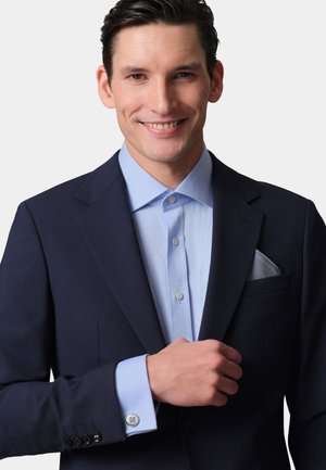 Navy suit jacket with a light blue dress shirt. Features include a textured fabric, visible buttons, and a patterned pocket square.