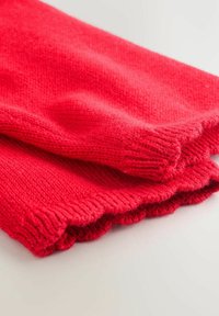 Rood gebreide stof met geribbelde mouwen en een gestructureerde afwerking. De randen zijn gegolfd, wat de algehele ontwerpdetaillering verbetert.