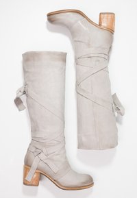 Bottes en cuir gris jusqu'au genou avec une surface texturée, dotées de sangles croisées et d'un talon en bois épais. Fini lisse, design élégant.