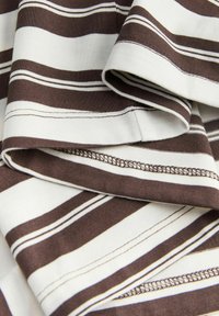 Striped fabric featuring alternating brown and white stripes with a smooth texture and visible stitching details.