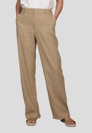 Pantalons beige à jambes larges avec une texture lisse, poches avant et taille cintrée. Associés à des sandales de couleur claire.