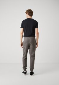 Camisa de manga corta azul marino combinada con pantalones grises de cintura elástica. El modelo lleva zapatillas negras y blancas. Tejido suave, ajuste casual.
