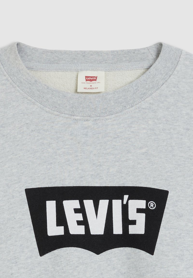 Felpa grigia con collo a giro, caratterizzata da una grafica nera a forma di logo Levi's sul petto. L'etichetta indica la taglia M, vestibilità comoda.