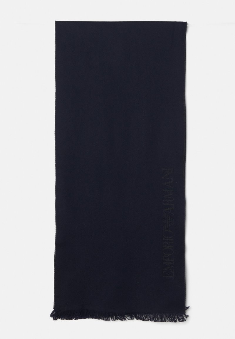 Sciarpa blu navy realizzata in morbido tessuto, con bordo frangiato e dettaglio del logo in rilievo lungo un lato. Forma rettangolare.
