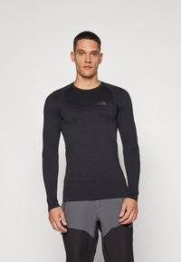 Langärmliges schwarzes Performance-Shirt mit strukturierten Einsätzen auf der Vorderseite, Rundhalsausschnitt und enganliegendem Design. Ideal für aktive Nutzung.